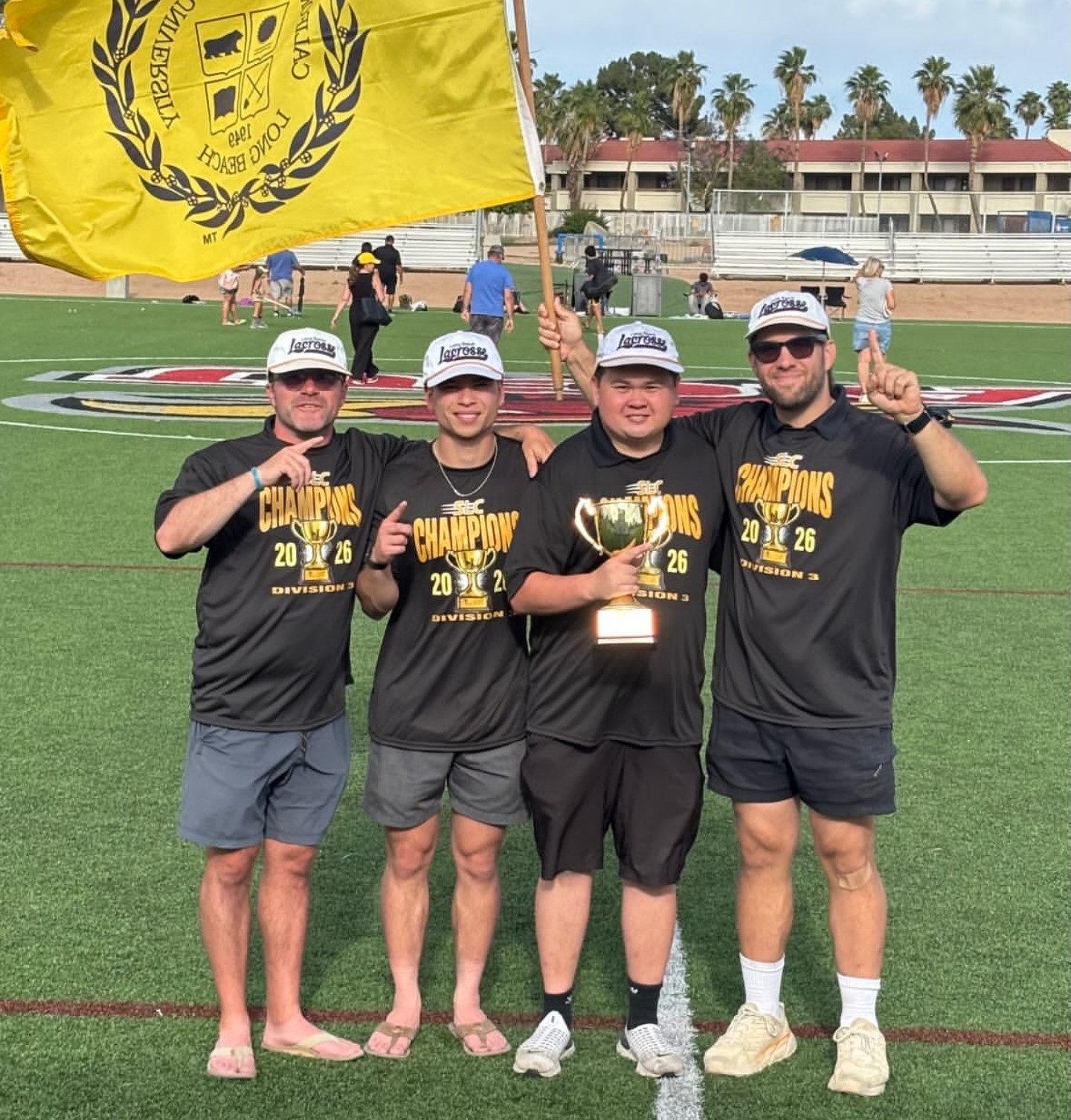Brett Fink celebrating the 2026 SLC championship with fellow members of the Cal State Long Beach lacrosse program, holding the trophy and team flag